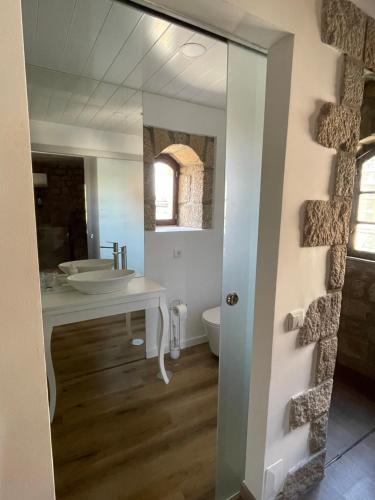 a bathroom with a sink and a toilet and a mirror at Casa do Torreão in Trancoso