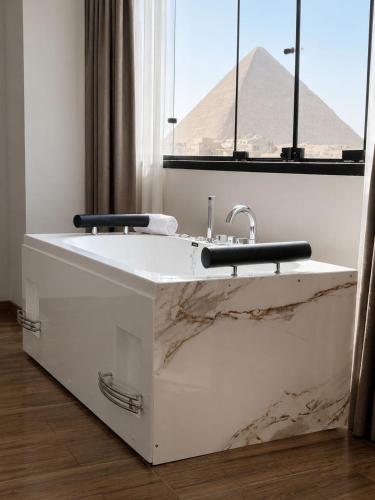 a bathroom with a marble sink with the pyramid in the background at Pyra King Royal Pyramids Hotel in Cairo