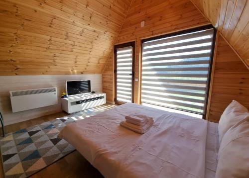 a bedroom with a bed and a tv in a room at La Casute Piatra Teiului in Poiana Largului
