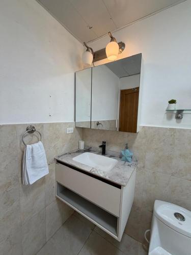 a bathroom with a sink and a mirror and a toilet at Cadaques Caribe Bayahibe Palmera in Bayahibe