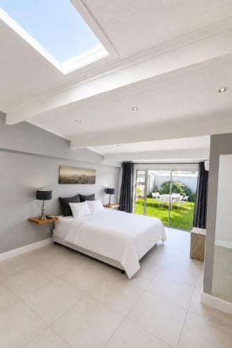a bedroom with a white bed and a large window at Pet-Friendly, 3-Bed, 2-Bath in Knysna Central in Knysna