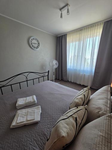 a bedroom with a large bed with a clock on the wall at Lake Breeze Stay in Liepāja