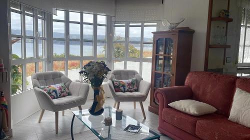 a living room with chairs and a table with a vase of flowers at Comfortable house with sea view in Viveiro, 200 m² in Viveiro