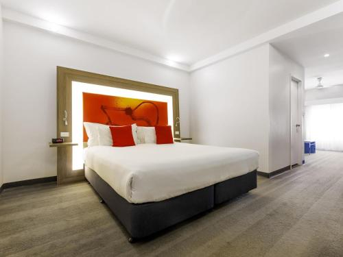 ein Schlafzimmer mit einem großen Bett und roten Kissen in der Unterkunft Novotel Darwin CBD in Darwin