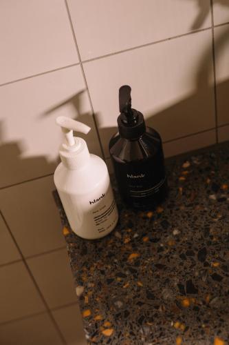 two bottles of soap sitting on a counter in a bathroom at The Hoxton, Shepherds Bush in London
