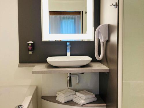 a bathroom with a sink and a mirror at ibis Styles Lille Aéroport in Lesquin