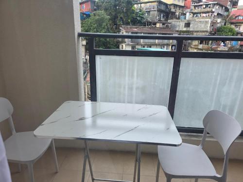 a white table and two chairs in front of a window at Megarich Studio in Megatower VII in Baguio