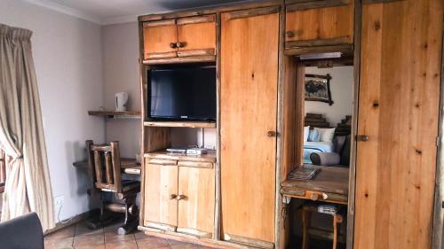a large wooden cabinet with a television in a bedroom at Aark Guest Lodge in Vanderbijlpark