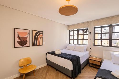 a bedroom with two beds and a chair and windows at One House by Anora Spaces in São Paulo