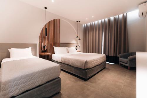 a hotel room with two beds and a chair at Golden Sun Hotel in Kalamaki