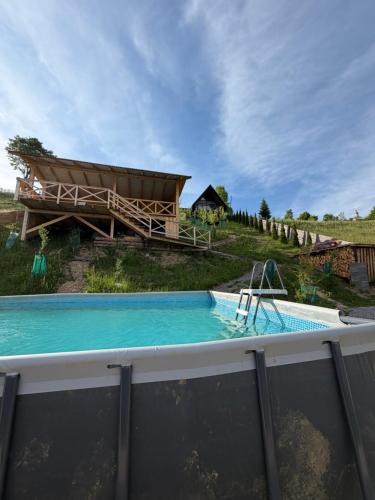 a swimming pool with a house in the background at У Ґазди in Synevyrsʼka Polyana