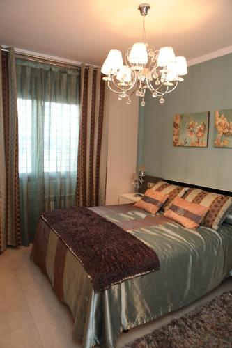 a bedroom with a large bed with a chandelier at Villa de Lujo con Piscina A 5 min de San Juan de los Terreros in Pulpí