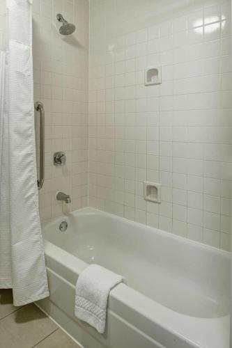 a white bathroom with a tub and a towel at AmericInn by Wyndham Brookfield in Brookfield