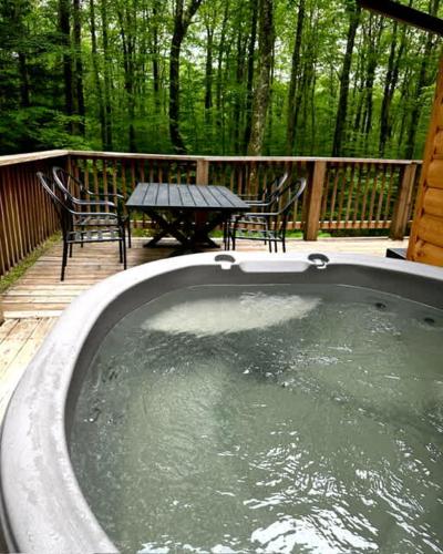 a hot tub on a deck with a table and chairs at Woodsy Way Cabin in Oakland