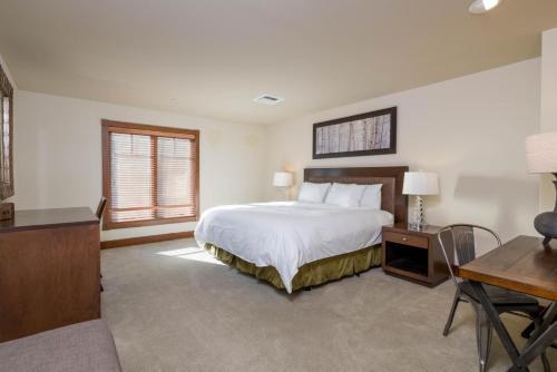 a bedroom with a white bed and a desk and a table at Chilali 25 in Ketchum