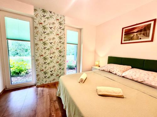a bedroom with a bed and a large window at Fűzliget2- Green Lake in Balatonfůzfő