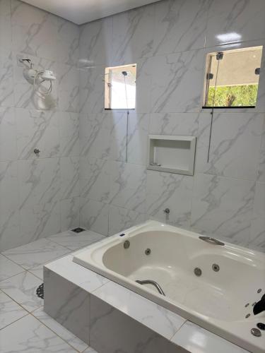 a white bathroom with a tub and a window at Recanto R2V in Chapada dos Guimarães
