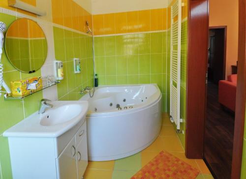 ein Badezimmer mit Badewanne, Waschbecken und Spiegel in der Unterkunft Hotel U Radnice in Louny