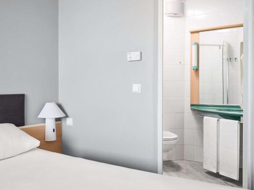 a bedroom with a bed and a bathroom with a sink at Ibis Częstochowa in Częstochowa