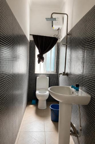 a bathroom with a white sink and a toilet at Caligeo Suites I in Ibadan
