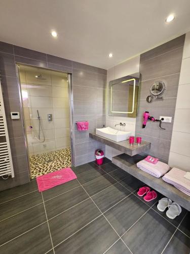 a bathroom with a sink and a shower with pink towels at La Bulle Des Anges in Illoud