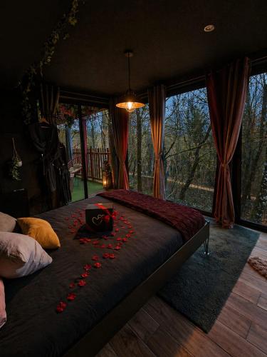 a bedroom with a bed with red rose petals on it at La Cabane Enchanteresse in Illoud