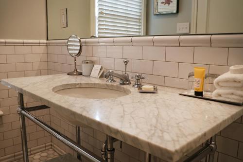 a bathroom counter with a sink and a mirror at The Virginia and Cottages in Cape May