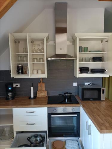 a kitchen with white cabinets and a stove top oven at Le Petit Manoir Vaillac in Fonmourenne