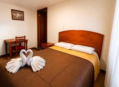 two white swans are sitting on a bed at Posada La Merced in Arequipa