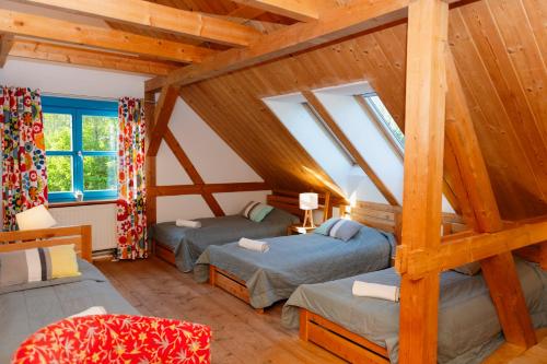 two beds in a room with wooden ceilings at Siedlisko Pod Strzechą in Wólka