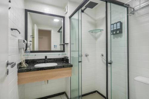a bathroom with a sink and a glass shower at Mar de Ponta Negra in Natal