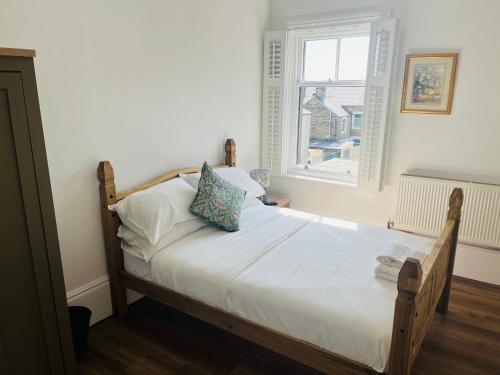 a bedroom with a bed with white sheets and a window at Venue Apartment in Colne