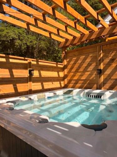a hot tub in a backyard with a wooden pergola at Log cabin with SPA, pool, and small beach in Mont-Tremblant