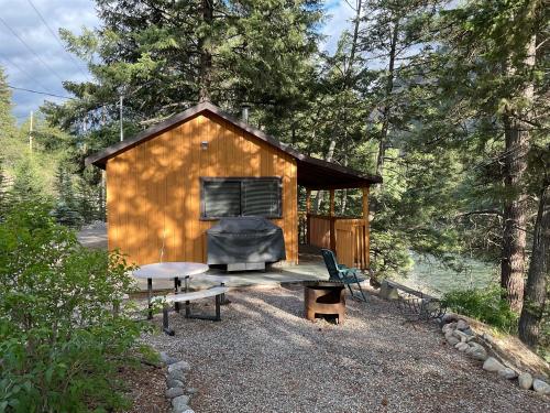 a cabin in the woods with a bench and a table at Doug's Emporium and Riverside Cabins in Hedley