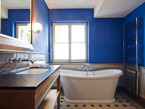 a blue bathroom with a tub and a sink at Auberge de Temple in Johannesberg