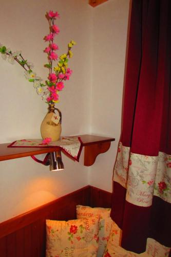a room with a bed and a vase with flowers on a shelf at Chata u vinára Milana, Tatralandia in Liptovský Mikuláš