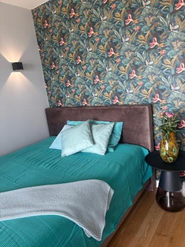 a bedroom with a green bed with a floral wallpaper at Apartamenty Laguna Przy Latarni in Darlowko