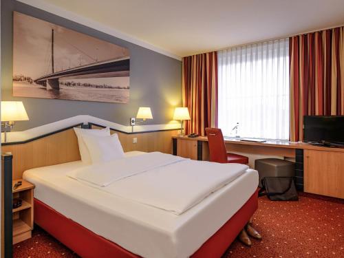 a hotel room with a large bed and a desk at Mercure Hotel Düsseldorf Ratingen in Ratingen
