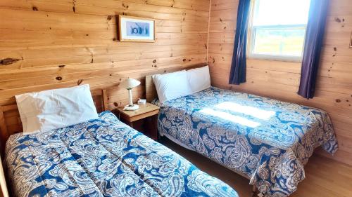 a bedroom with two beds in a log cabin at Blue Spruces Cottages in Hampton 