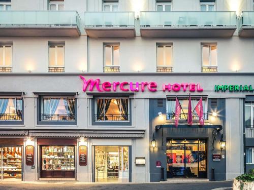 a store front of a hotel with a neon sign at Mercure Lourdes Impérial in Lourdes