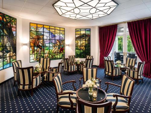 a meeting room with tables and chairs and stained glass windows at Mercure Lourdes Impérial in Lourdes