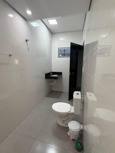 a white bathroom with a toilet and a sink at Lotus in Gurupi