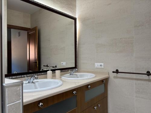 a bathroom with two sinks and a large mirror at A Casita do Ferreiro in Sober