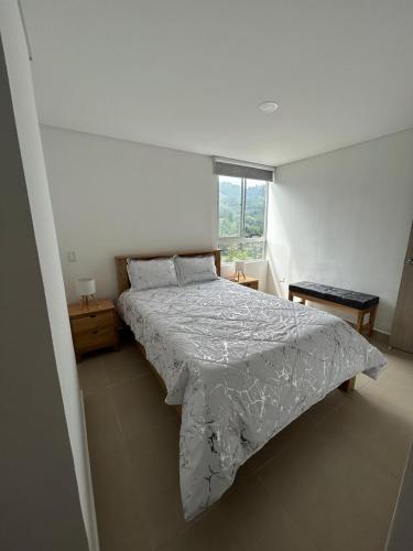 a bedroom with a bed with a comforter and a window at Atardeceres de Sabaneta in Sabaneta