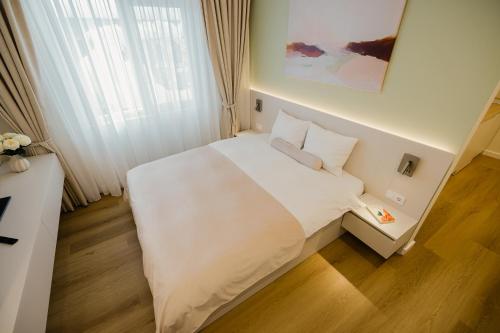 a bedroom with a white bed and a window at Camelia's cozy place in Baia Mare