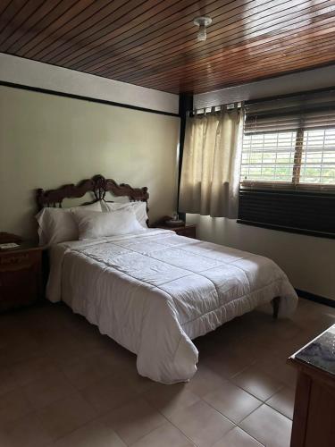 a bedroom with a large white bed with a window at Apartamento Amoblado Refugio Mérida in Mérida