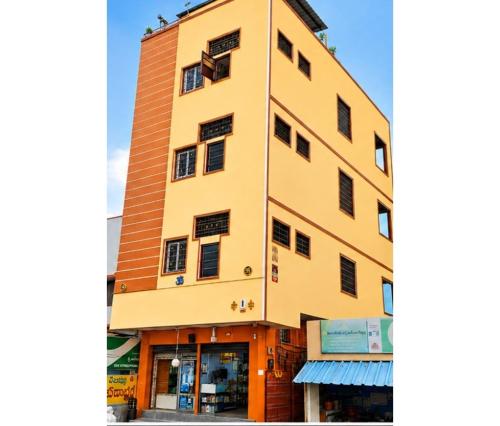 a tall yellow building with a store at Jyothi swaroop bhakta nivas in Tirupati