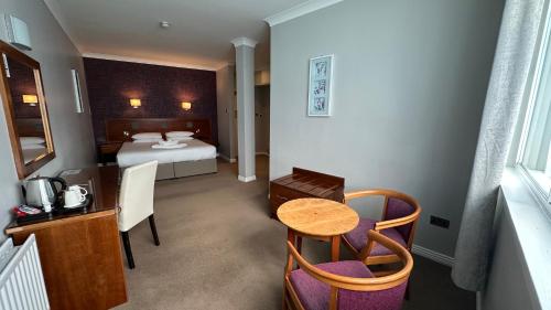 a hotel room with a bed and a table and chairs at Imperial Hotel Galway in Galway