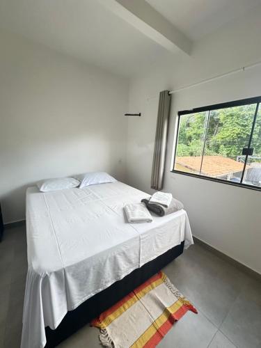 a bedroom with a white bed with a window at Pousada caminho das águas in Pirenópolis