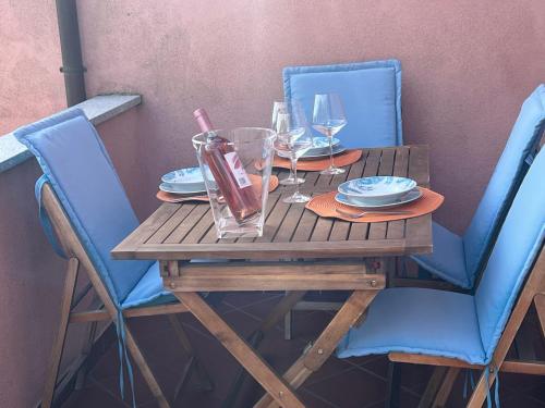 a wooden table with two blue chairs and glasses at Appartamento Marisa2 a soli 200mt dal mare e vista mare in Fetovaia